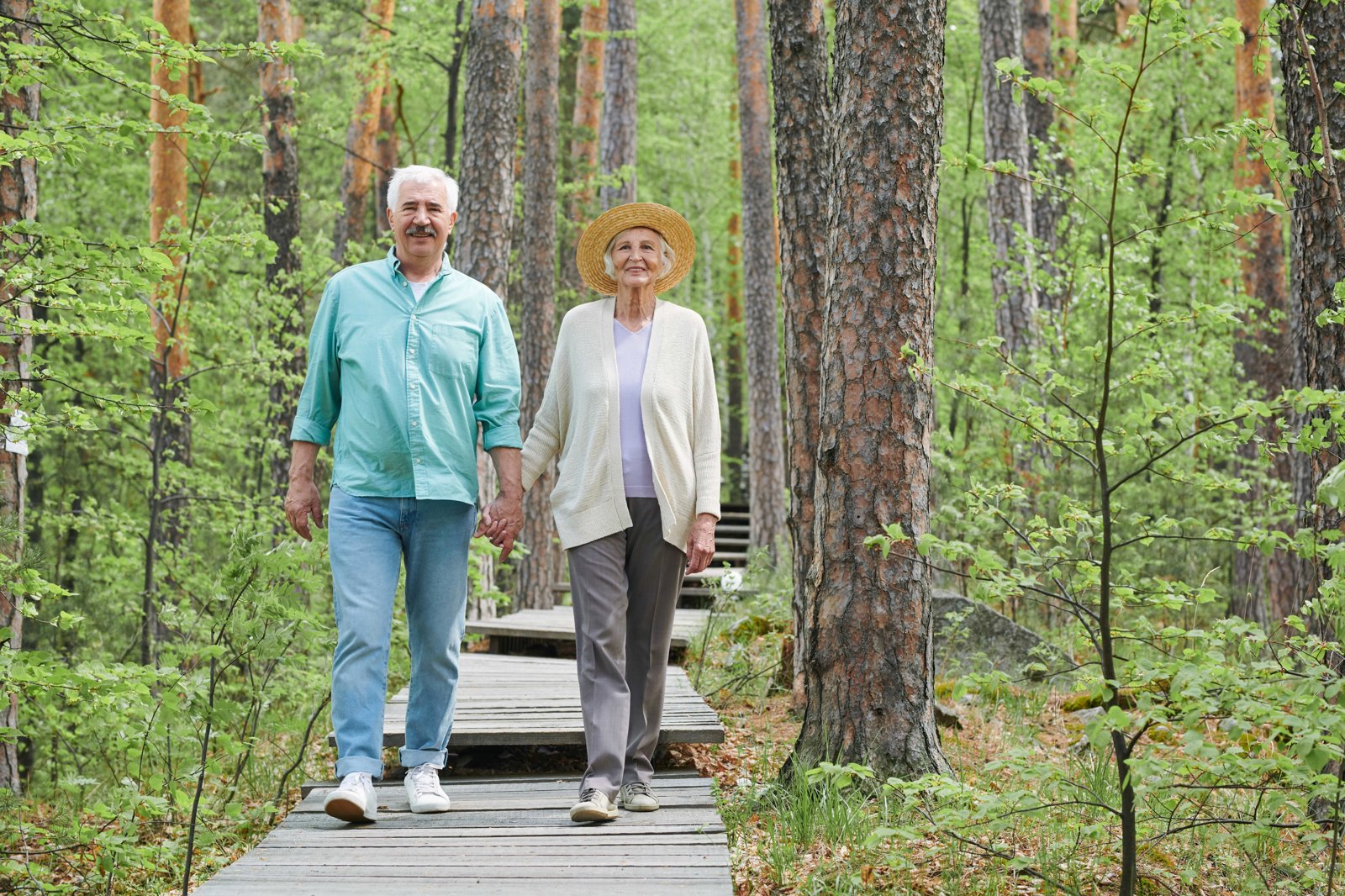 Happy Aged Retired Man Woman Holding By Hands While Moving Down Forest Path Among Trees Leisure