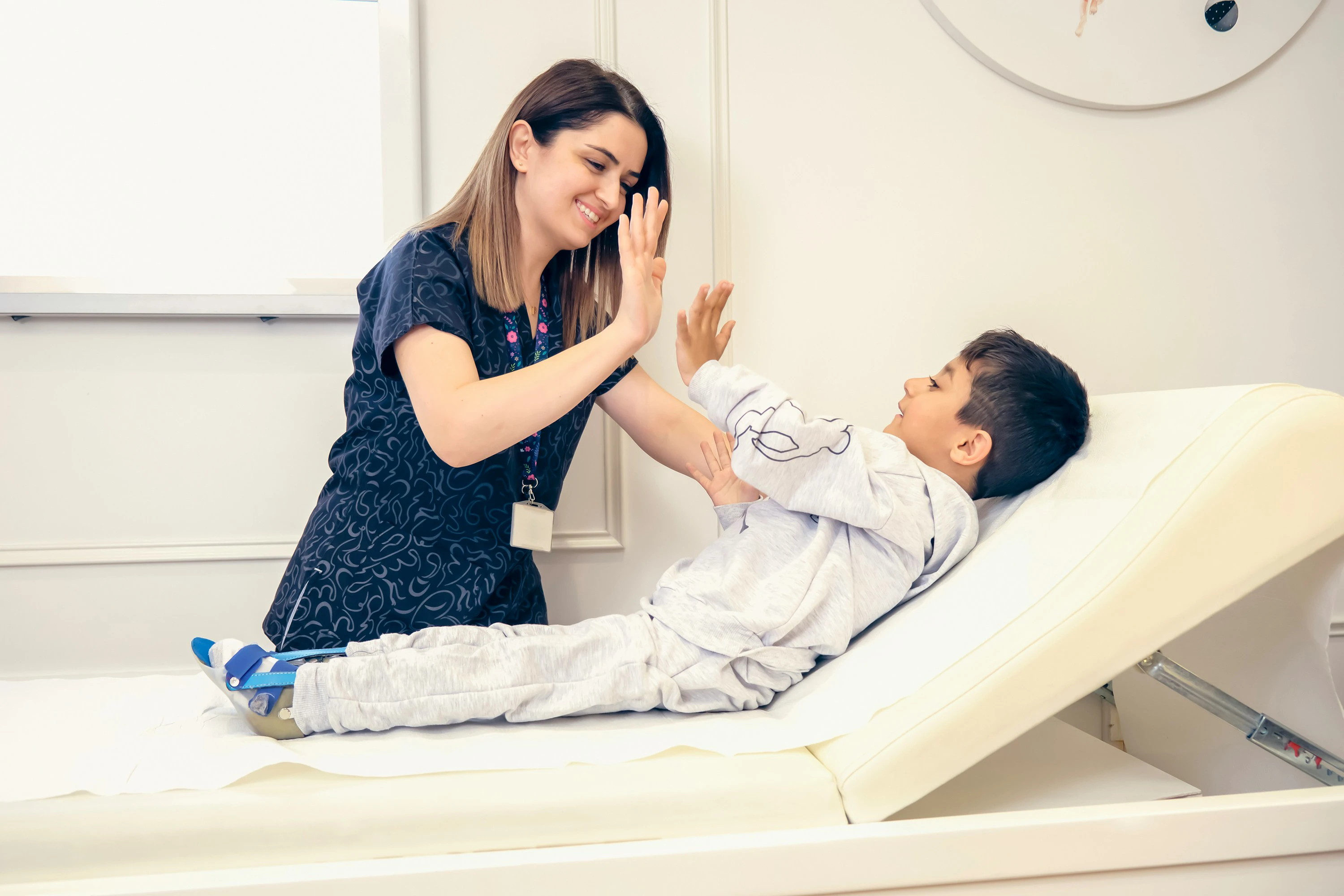 Un enfant portant des chaussures orthopédiques tape dans la main d'un employé du Foot Care Center