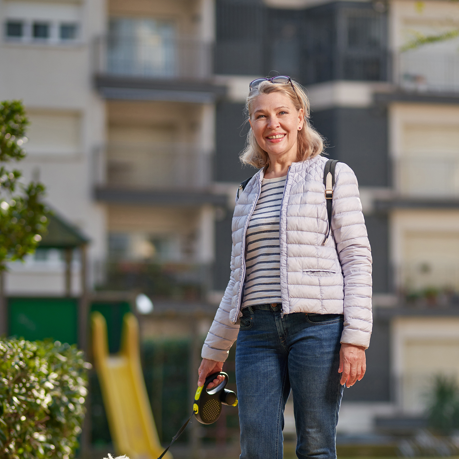 Middle Aged Blond Woman Walking With Fluffy White Dog Summer City