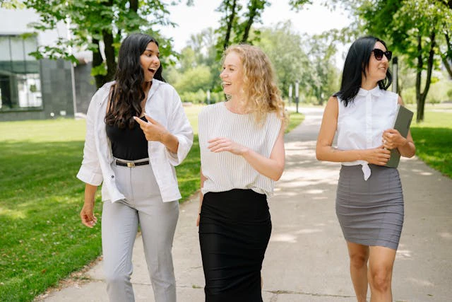 Trois femmes souriantes portent des bas de contention du Foot Care Center by Spronken Orthopedie lors d'une promenade dans le parc.